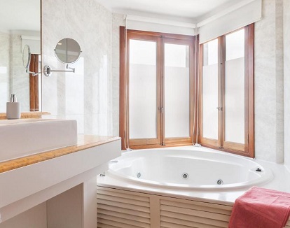 Foto de la bañera de hidromasaje de forma circular en un altillo junto a la ventana del bano de la Suite Junior del hotel Eden Binibeca