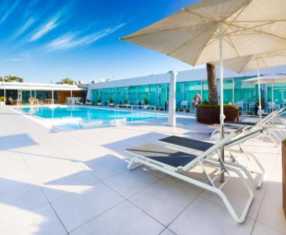 Amplia piscina con tumbonas rodeada de algunas de las habitaciones de este hotel con encanto.