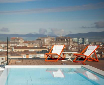 Terraza con piscina, solarium y vistas a la ciudad de este hotel con encanto.