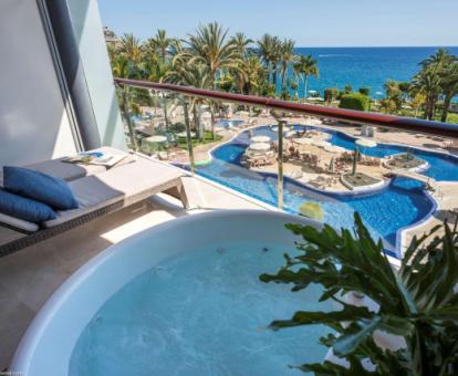 Terraza con jacuzzi privado y vistas a la piscina y al mar de una de las modernas habitaciones del hotel.